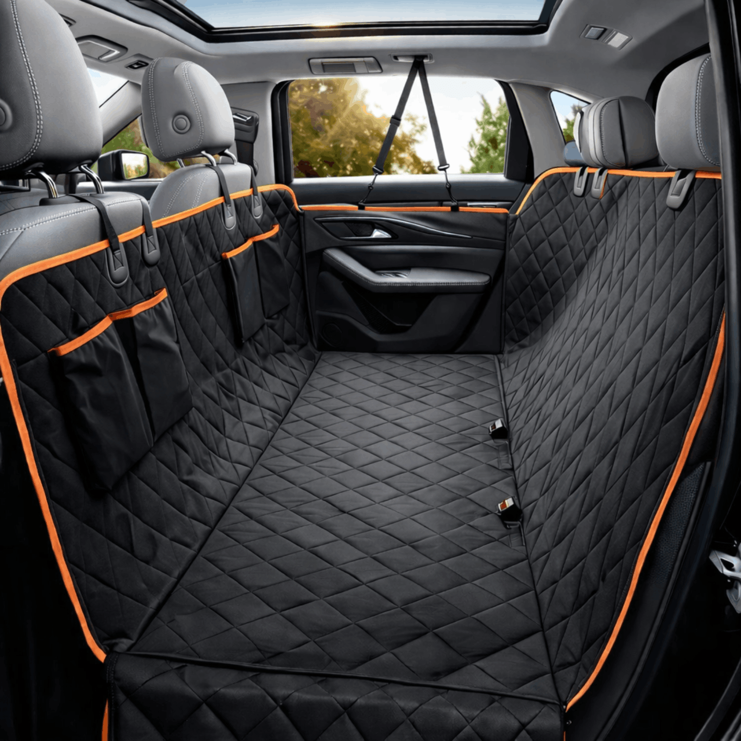 Black quilted car seat cover protecting the back seat with orange trim and headrest straps installed.