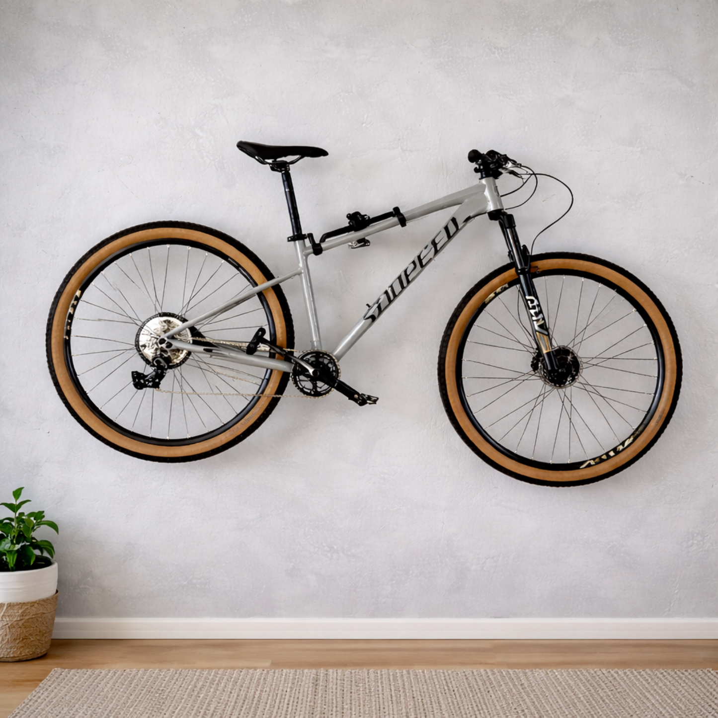 Zilverkleurig fiets ophangsysteem aan de muur met een mountainbike horizontaal opgeborgen in een woonkamer.