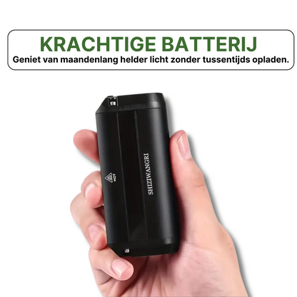 Compacte zwarte Shinzwanger batterij voor fietslamp vastgehouden in hand met witte achtergrond.