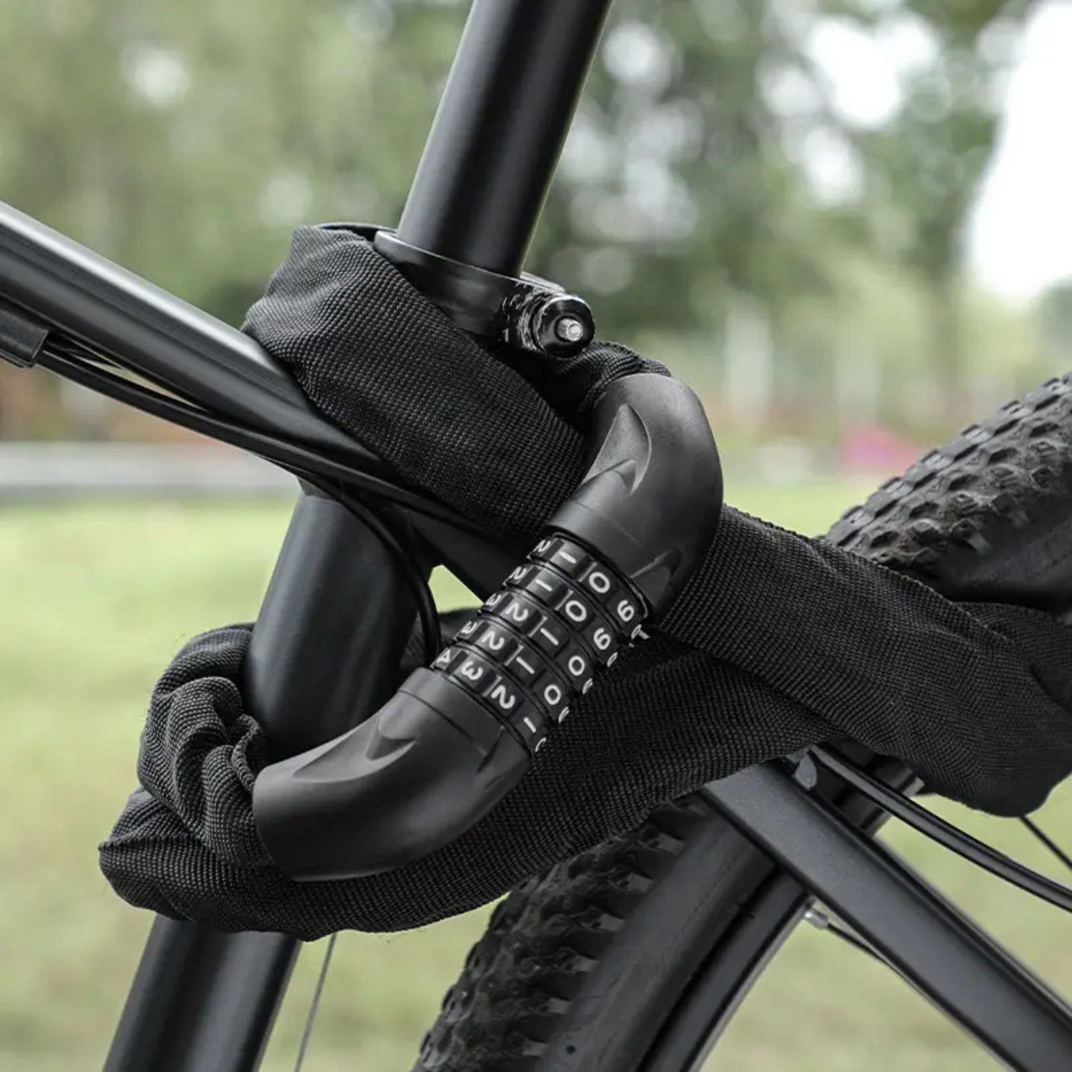 Zwart kettingslot met cijferslot bevestigd aan frame en wiel van een mountainbike in buitenomgeving.
