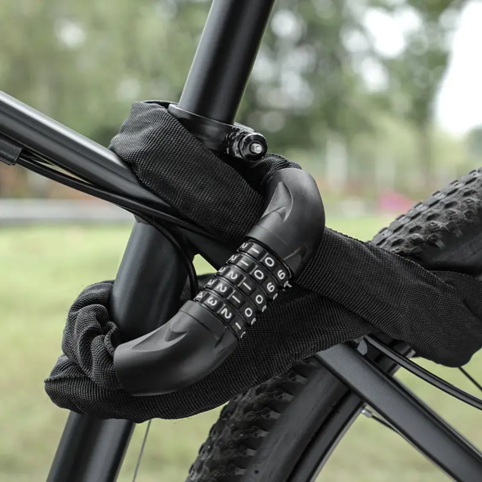 Zwart kettingslot met cijferslot bevestigd aan frame en wiel van een mountainbike in buitenomgeving.