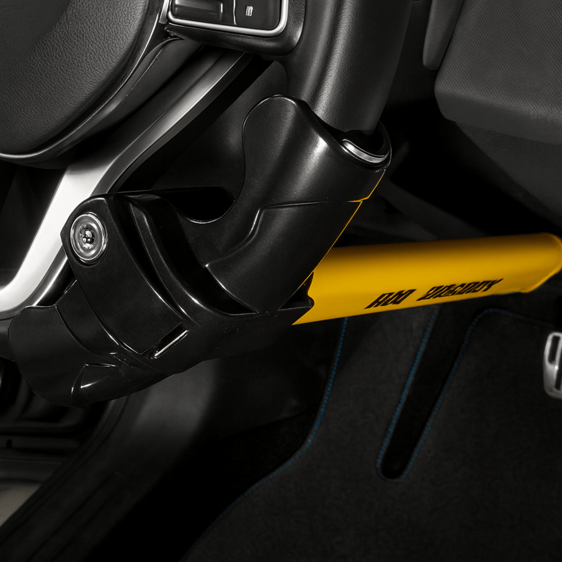 Side view of a yellow-black steering lock attached to the steering wheel and pedal for theft protection.