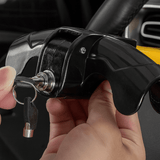 Close-up of hands inserting a key into a black steering lock to secure the steering wheel.