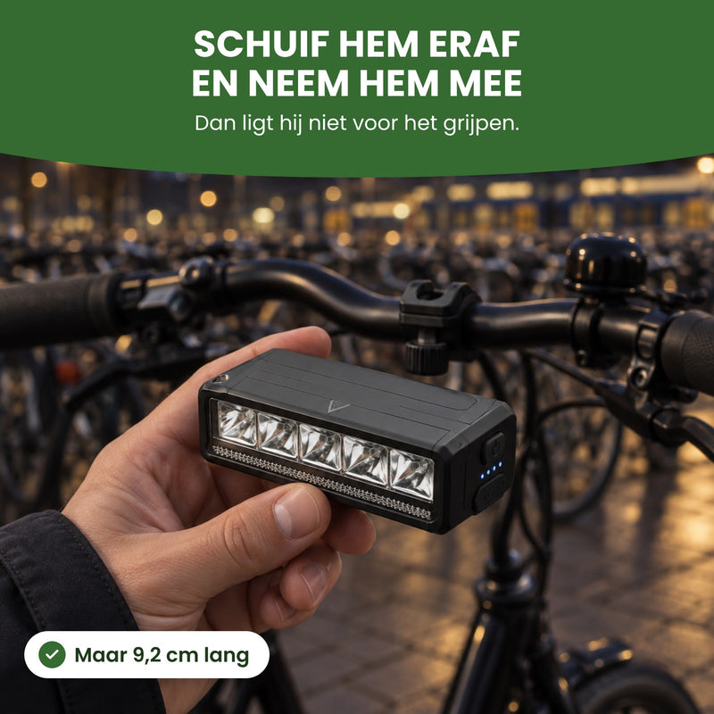 Voltura bike light held in a hand next to a parked bike: slide it off and take it with you, 3.6 inches long